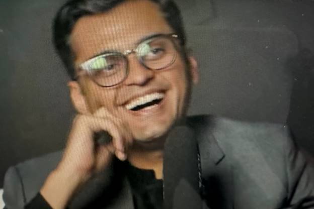 A person in glasses smiling Description automatically generated