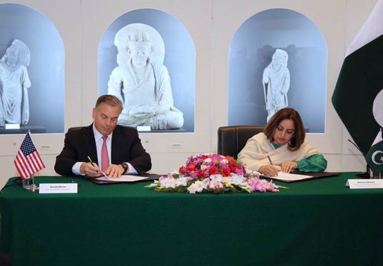 Ambassador Blome and Secretary Humaira Ahmed of National Heritage and Culture sign the U.S.-Pakistan cultural property agreement, aimed at safeguarding Pakistan’s extraordinary cultural treasures, with the document prominently displayed on the table beside them.