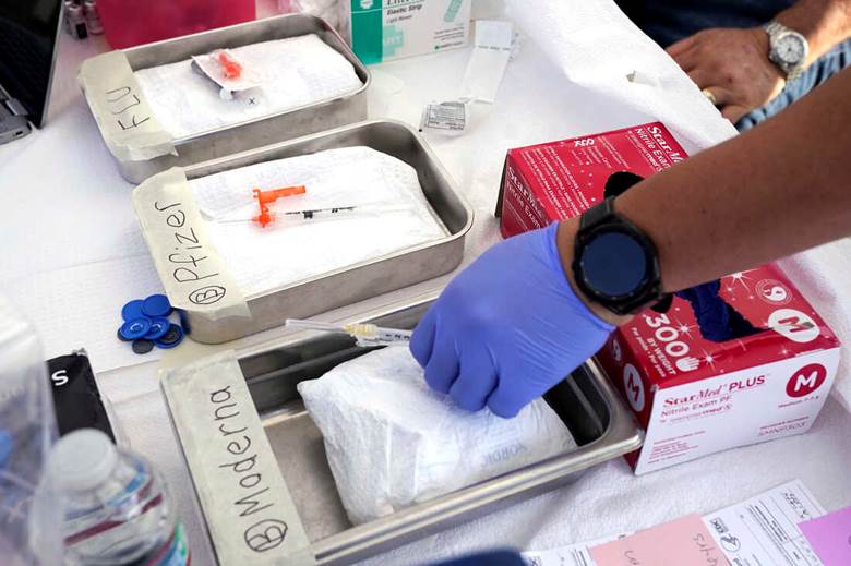 A person in gloves putting a syringe into a tray  Description automatically generated