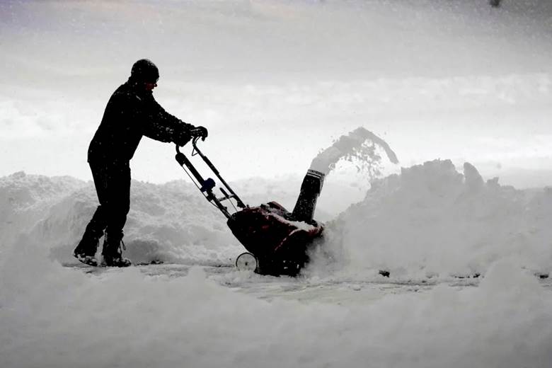A person clears snow with a snow blower.