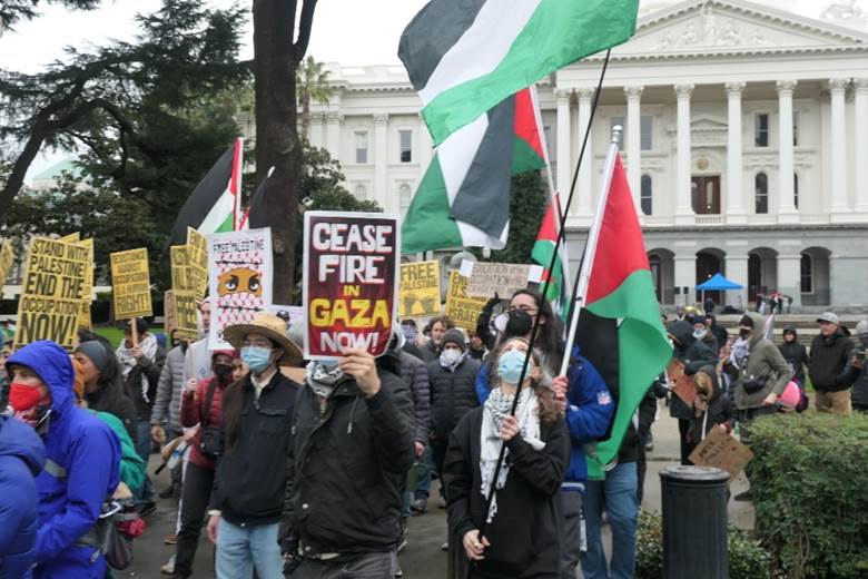 A group of people holding signs and flags  Description automatically generated