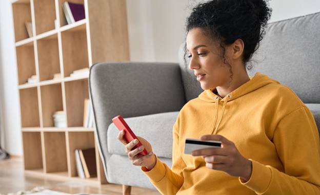 A person holding a credit card and a phone Description automatically generated