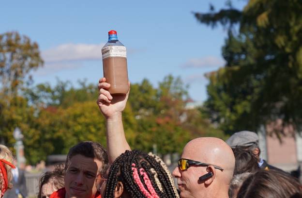 A person holding a bottle of liquid  Description automatically generated