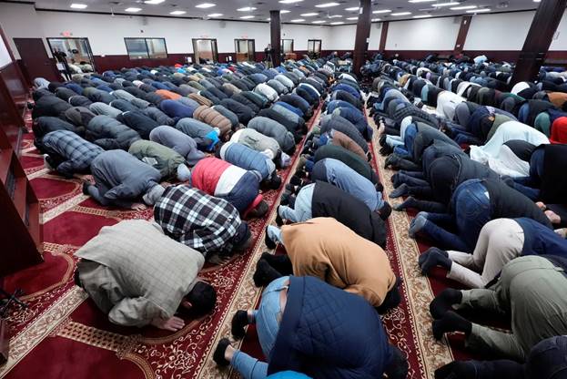 A group of people praying in a room Description automatically generated