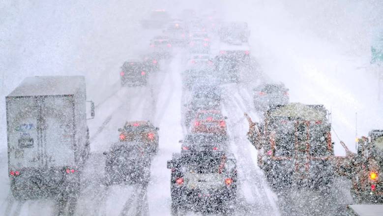 Plows, at right, try to pass nearly stopped traffic due to weather conditions in Londonderry, N.H., in March 2023.