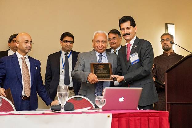 A group of men standing around a table with a person holding a plaque Description automatically generated