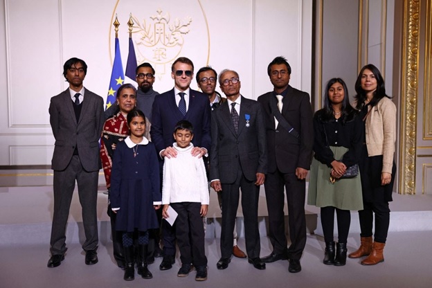 French President Emmanuel Macron (C-L), wearing sunglasses, poses with Akbar and his relatives after awarding the Chevalier of the French Order of Merit to Ali Akbar, who hawks newspapers around the streets of Saint-Germain-des-Pres in the French capital for 50 years, at the Elysee Palace in Paris on January 28, 2026.AFP