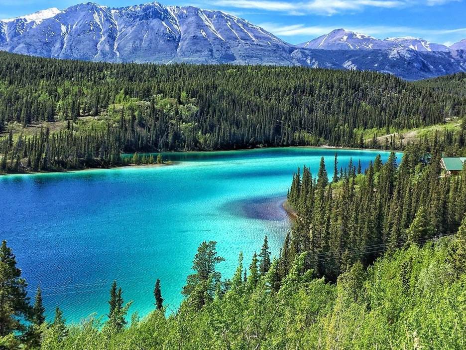 A lake surrounded by trees and mountains Description automatically generated with medium confidence