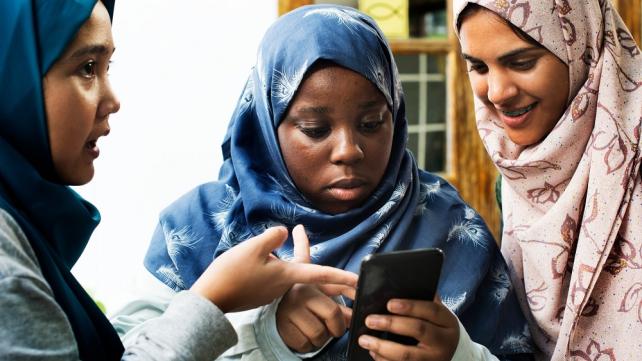 A group of women looking at a phone  Description automatically generated