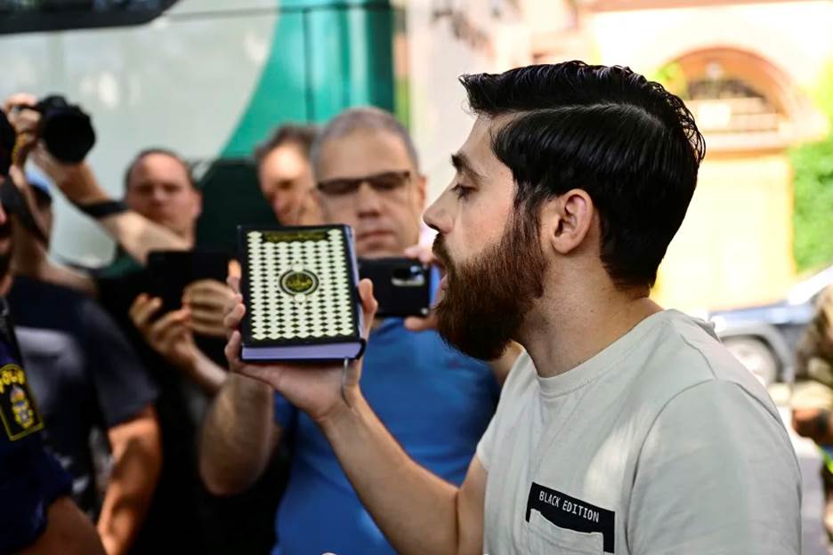 A man talks to the media outside the Isaeli embassy in Stockholm, Sweden, July 15, 2023. The man who said he would burn the Torah and the Bible outside the Israeli Embassy in Stockholm gave up his plan and instead held a one-person demonstration against burning holy books. (Magnus Lejhall/TT News Agency via AP)