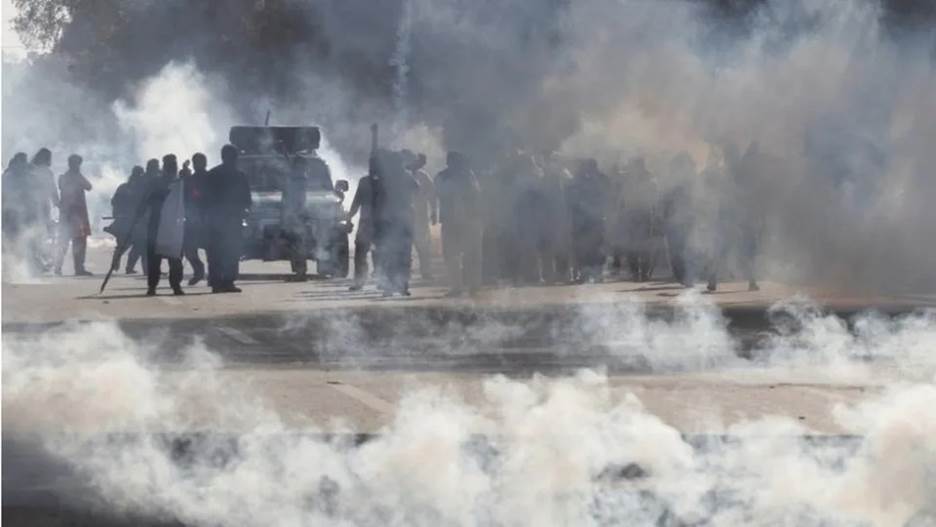 Supporters of former Prime Minister Imran Khan, react amid tear gas smoke, fired by the police to disperse them during clashes ahead of an election campaign rally, in Lahore, Pakistan (March 8, 2023).