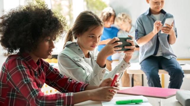 A group of kids looking at their phones  Description automatically generated