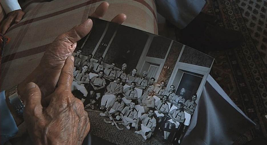 A hand holding a photo of a group of people Description automatically generated