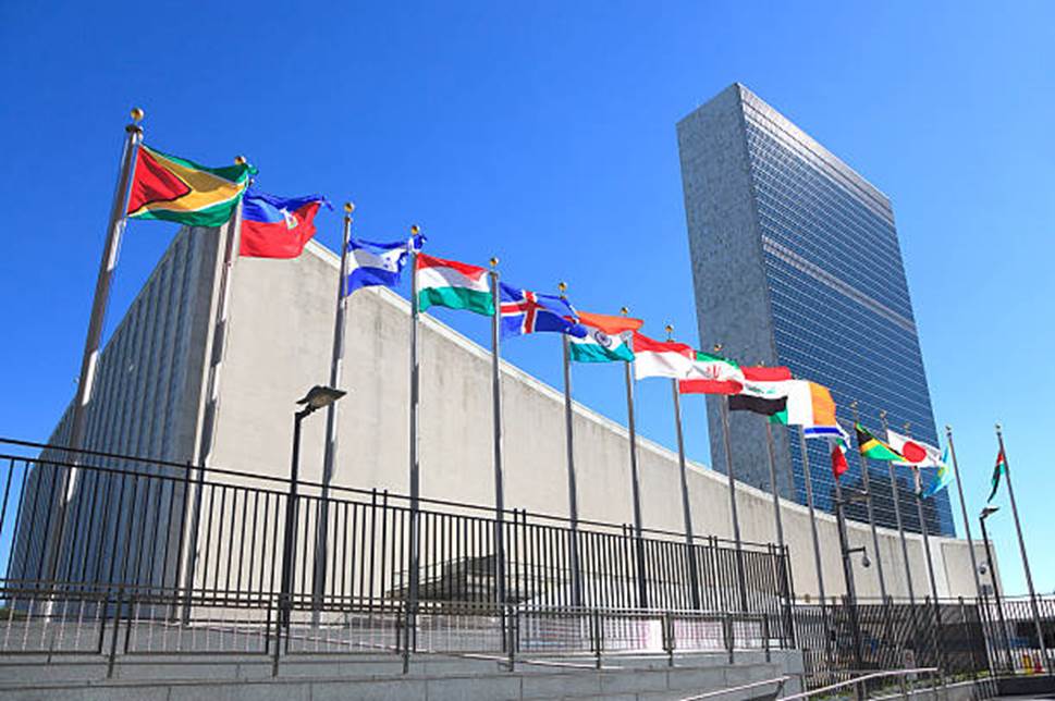 A group of flags in front of Headquarters of the United Nations  Description automatically generated