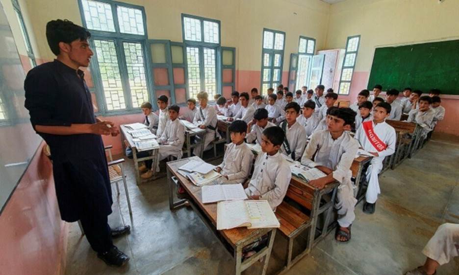 Israr Ahmed, (R - 2nd row) who survived after being rescued from a stranded cable car, sits with other children in a classroom at a school in Battagram, KP, on August 23, 2023.