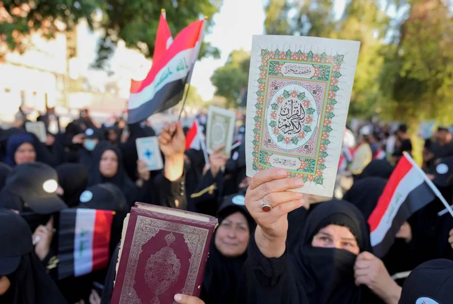 A group of people holding flags and books Description automatically generated