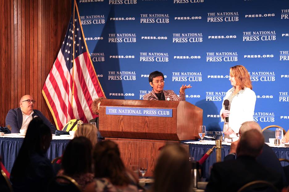 A person speaking at a podium with a person in front of him Description automatically generated