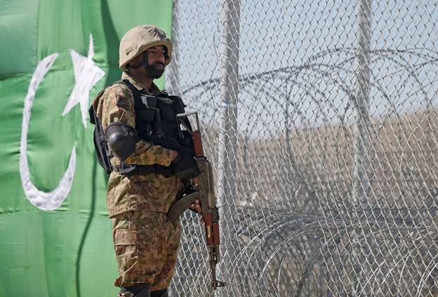 A soldier standing next to a fence  Description automatically generated