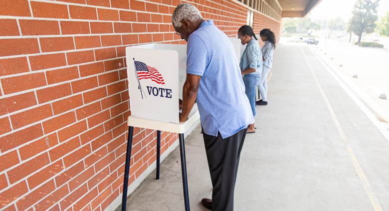 A person putting his vote into a ballot box Description automatically generated