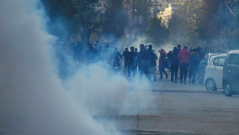 A group of people walking on a street with smoke  Description automatically generated