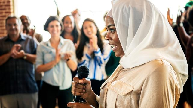 A person holding a microphone Description automatically generated