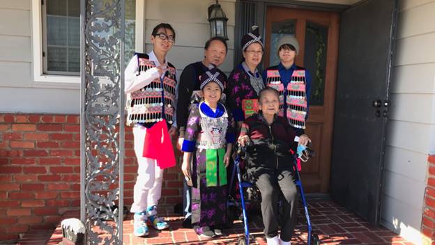 A group of people standing in front of a house  Description automatically generated