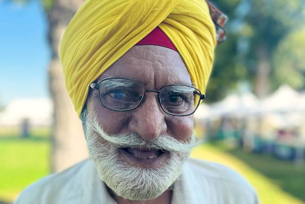 A person with a mustache and yellow turban  Description automatically generated