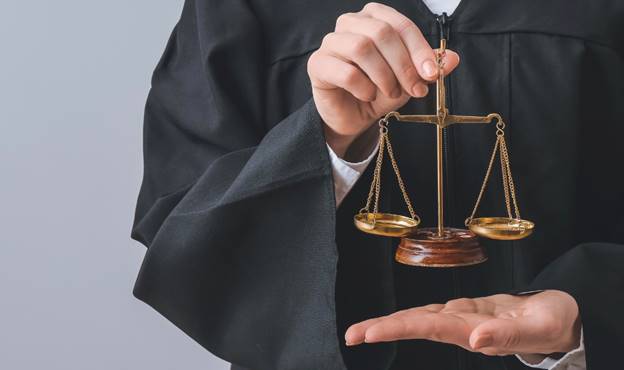 A judge holding a scale Description automatically generated