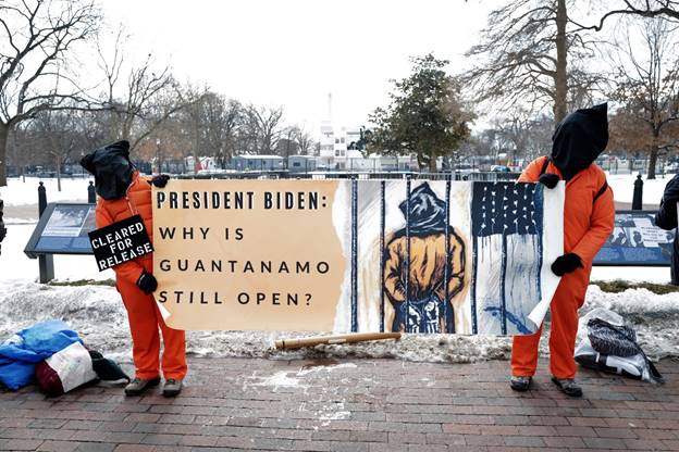 A group of men holding a sign  Description automatically generated